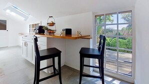 A modern kitchen with a built-in oven, a fruit basket, and a coffee maker on the counter.
