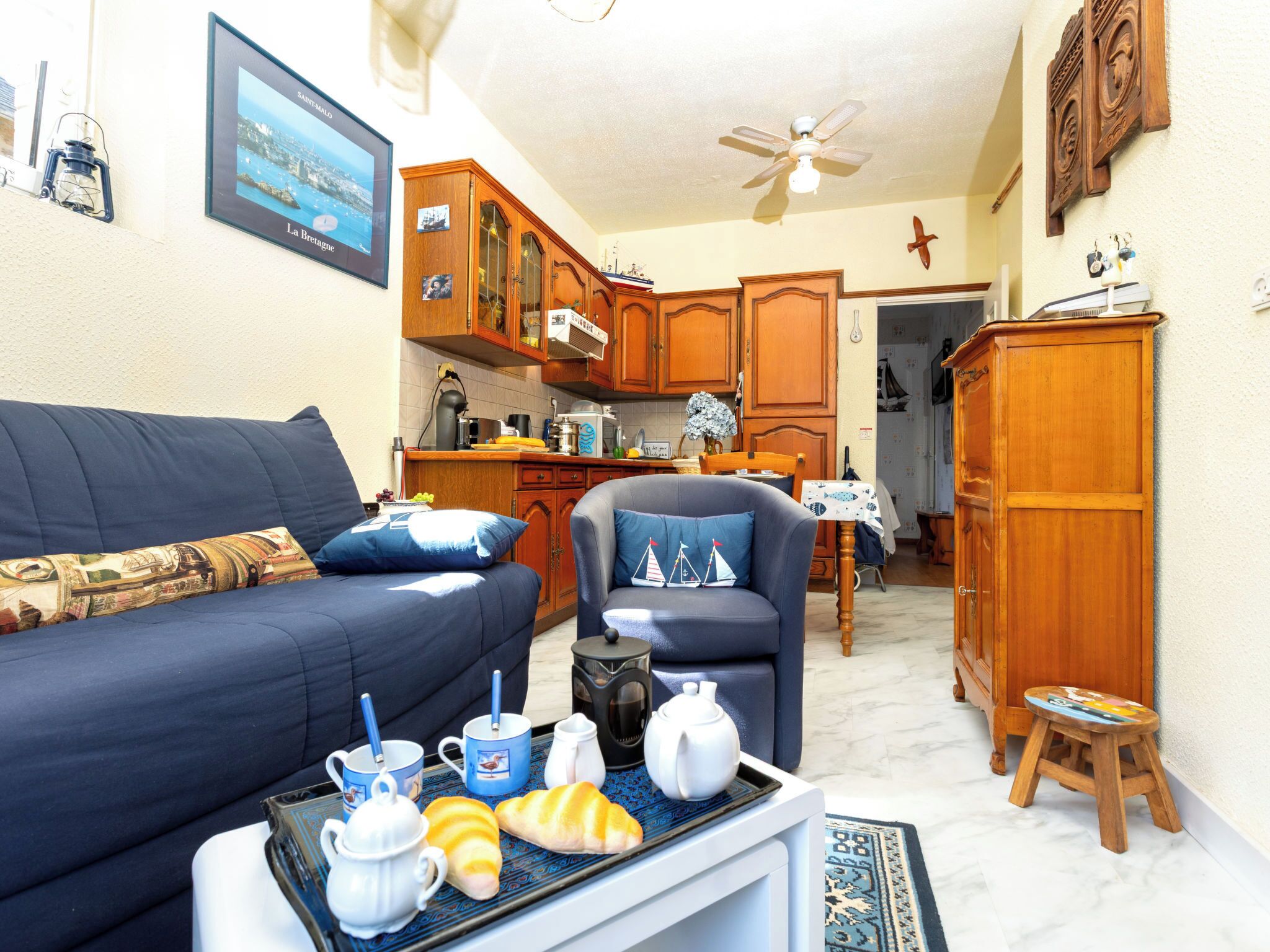 Ein gemütliches Wohnzimmer mit einer Couch, einem Sessel und einem Couchtisch mit Frühstücksgebäck.