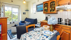 A cozy kitchen with a dining table set for two, wooden cabinets, and a view of the outdoors. - Theophile by Interhome (Saint Malo)