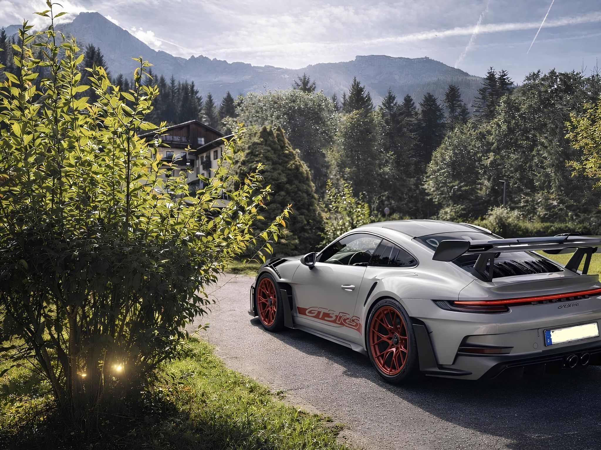 A luxury car parked on a road with a mountainous backdrop.