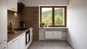 Una cocina moderna con armarios blancos, una estufa negra y una ventana con vistas a árboles.