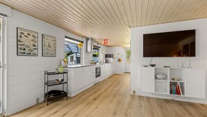 Eine moderne Küche mit weißen Schränken, einer zentralen Kochinsel und einem großen Flachbildfernseher an der Wand.