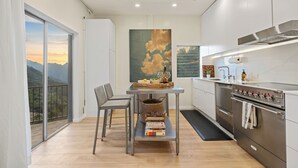 Una cucina moderna con un'ampia finestra, un tavolo da pranzo con sedie e vista sulle montagne.