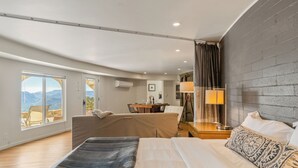 Une chambre d’hôtel moderne dotée d’un grand lit, d’un canapé, d’un coin repas et offrant une vue sur les montagnes.