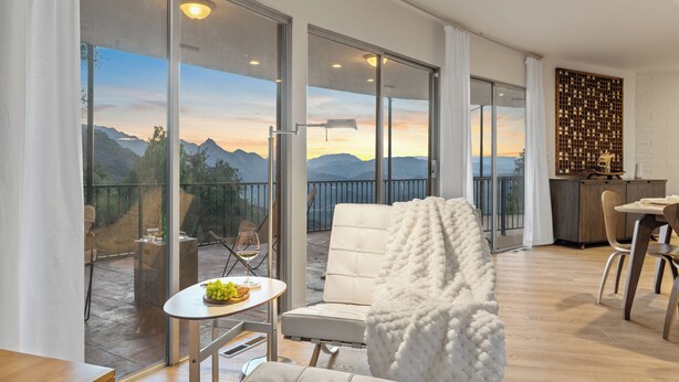 Un salon moderne doté d’une grande porte-fenêtre coulissante donnant sur un balcon avec vue sur les montagnes.
