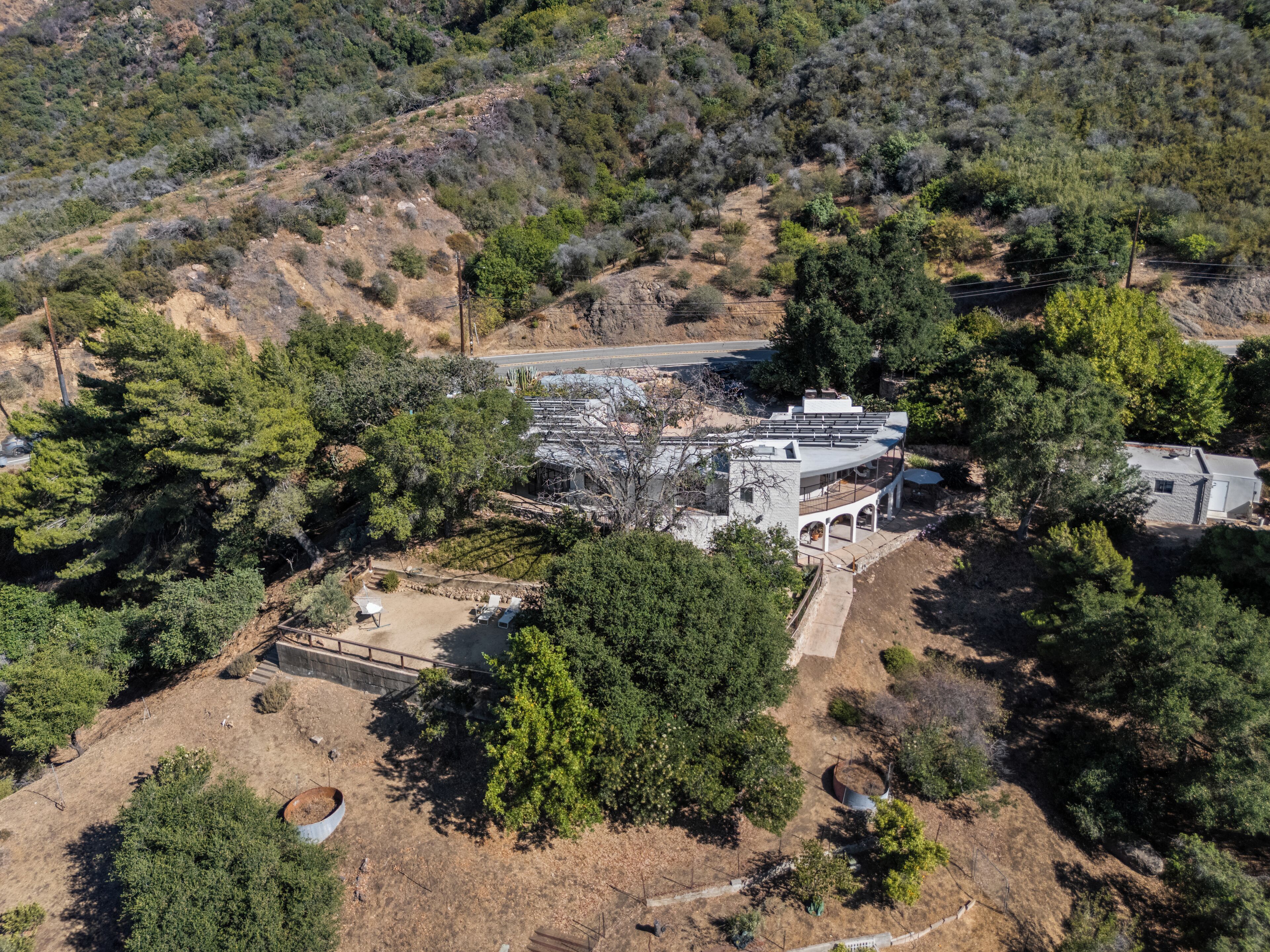 Vue aérienne d’une propriété comprenant un grand bâtiment, une allée pavée et des arbres environnants.