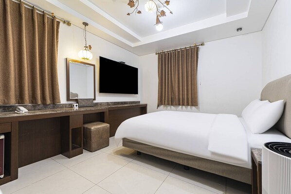 A modern hotel room with a large bed, a flat-screen TV, a vanity with a mirror, and a chandelier. - Youngdeungpo CIEL Hotel. (Seoul)