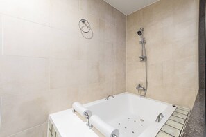 A modern bathroom with a bathtub, shower, and toilet.