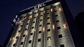 A hotel with a brick facade, multiple windows, and a sign reading "CEL HOTEL".