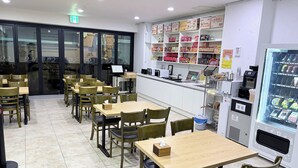 A restaurant with wooden tables and chairs, a vending machine, and shelves stocked with snacks.