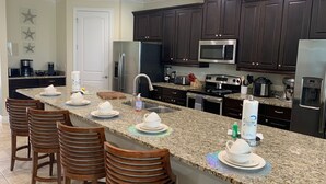 A modern kitchen with dark wood cabinets, stainless steel appliances, and a granite countertop.