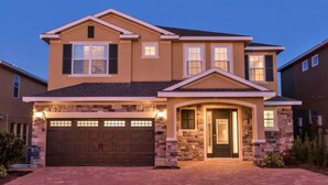 A two-story house with a stone facade, a garage, and a well-lit front door.