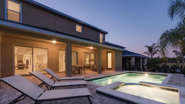 A modern house with a swimming pool, lounge chairs, and a patio area.