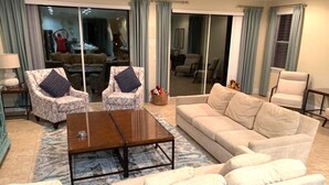 A living room with a beige sofa, two patterned armchairs, a wooden coffee table, and a blue patterned rug.