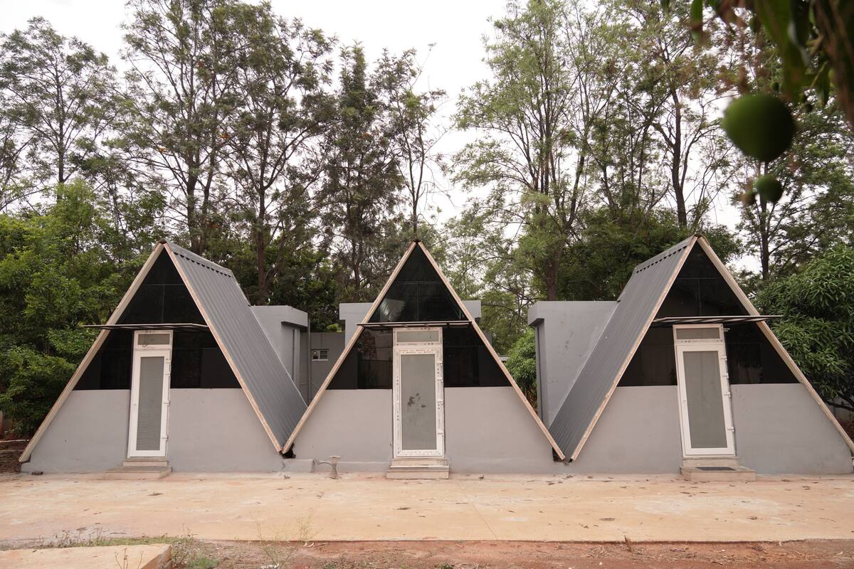 Three triangular tents with doors, set in a natural environment with trees.