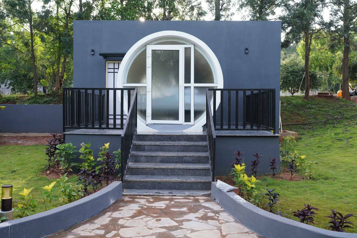 A modern building with a circular window, a staircase leading to a balcony, and a stone pathway.