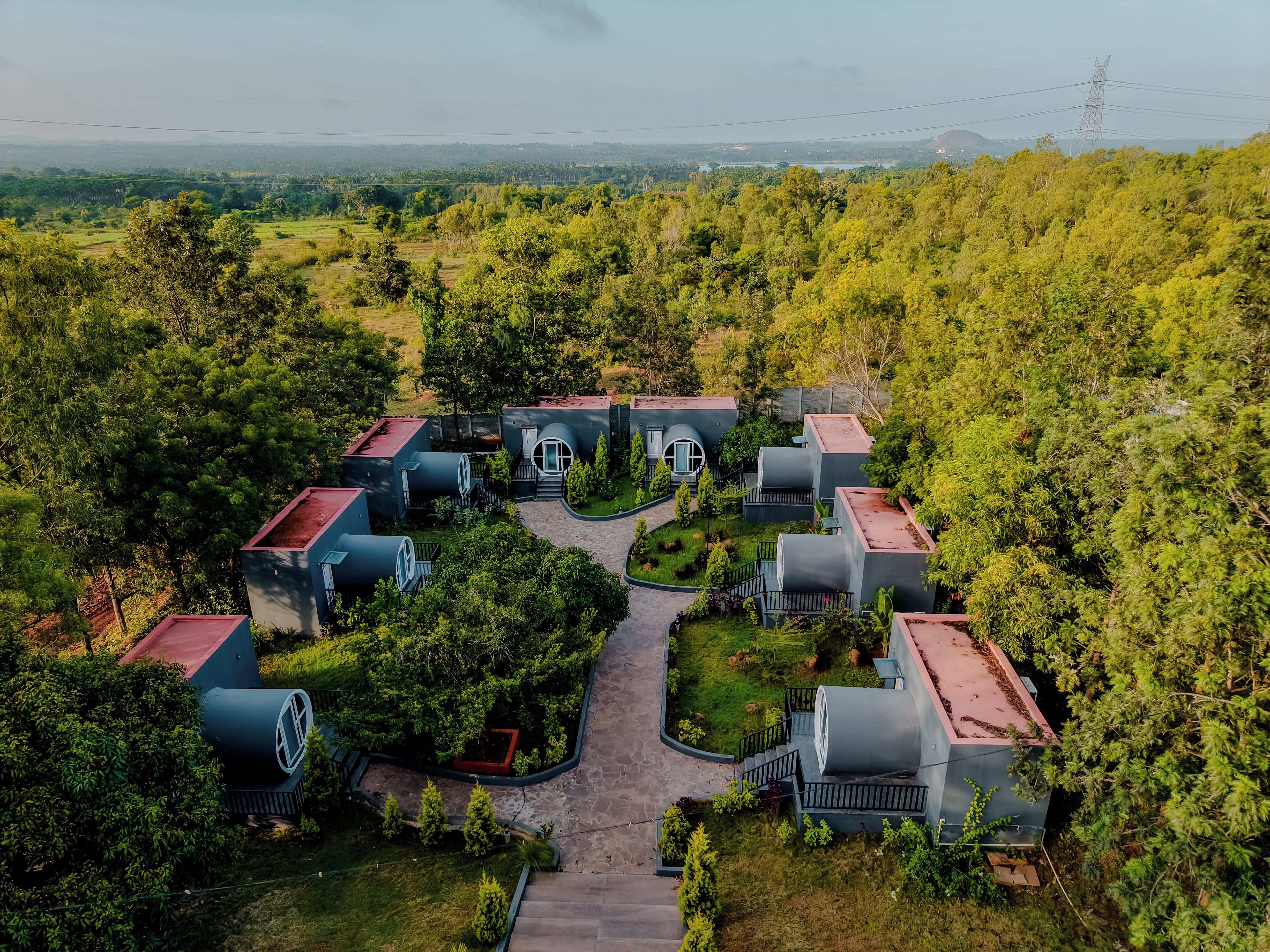 Un barrio residencial con casas cilíndricas, un paseo central y vegetación circundante.