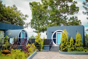 A modern building with two circular windows and a stone pathway leading to the entrance. - Benchkal Resort (Tumkur)