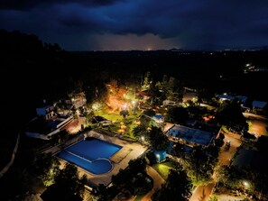 A residential area with a swimming pool, a tennis court, and a well-lit park area at night. - Benchkal Resort (Tumkur)