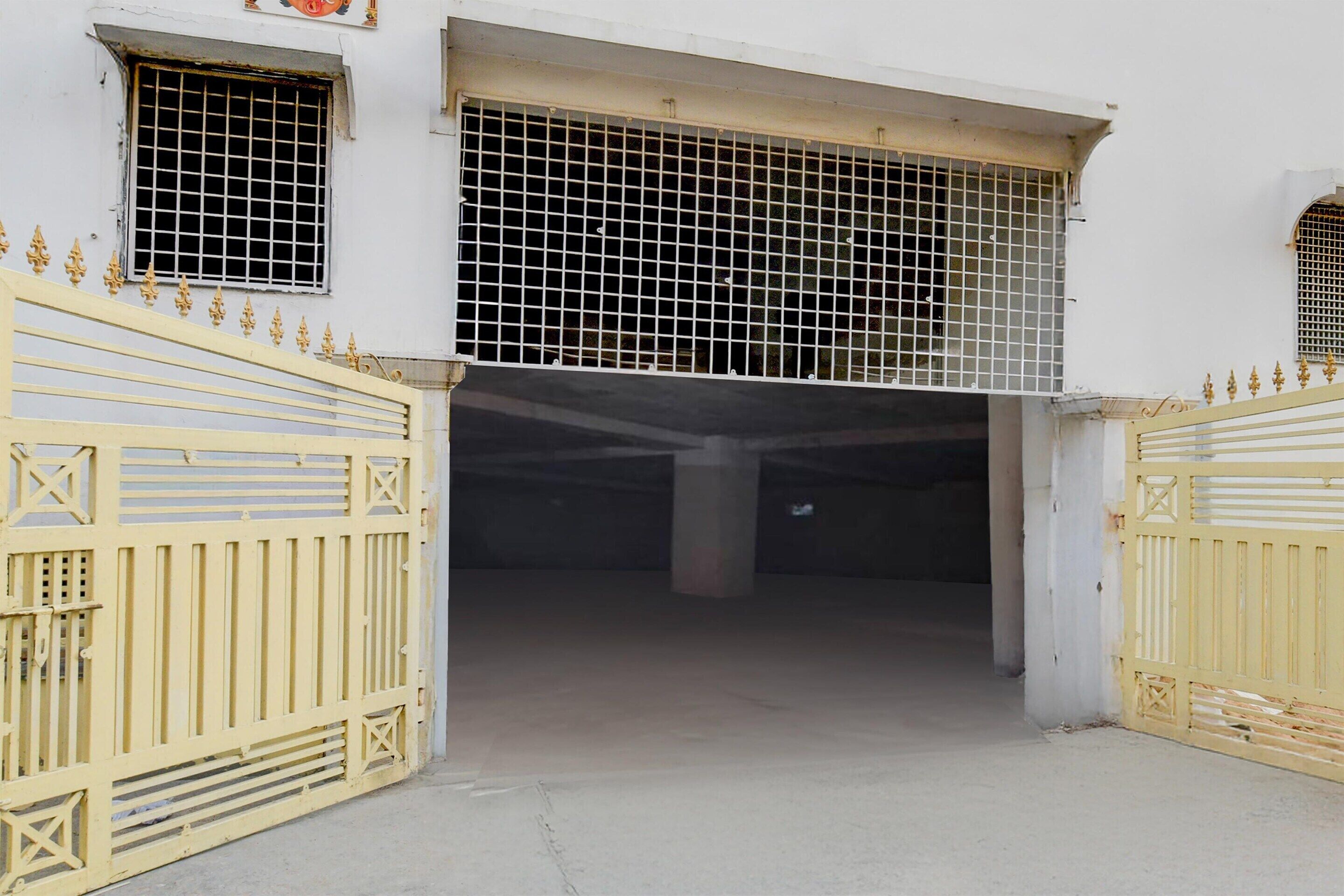 A building entrance with a yellow gate, a window with a metal grille, and a concrete floor.