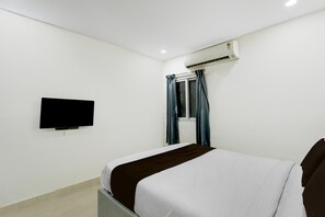 A hotel room with a bed, a flat-screen TV mounted on the wall, and an air conditioning unit. - Super Townhouse Nagole RTO Office (Hyderabad)