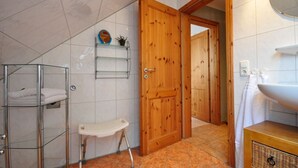 Een badkamer met een houten deur, een witte wastafel, een glazen plank en een wit toilet.