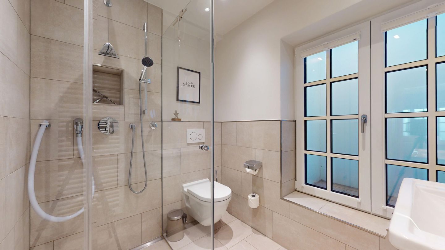 Un bagno moderno con doccia vetrata, un water e una finestra con vista.