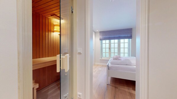 A bedroom with a bed, a window with blinds, and a wooden ceiling.