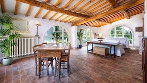 A rustic dining area with a wooden table and chairs, arched windows, and a brick floor. - Villa in Badia A Passignano with 9 bedrooms sleeps 18 (Badia A Passignano)
