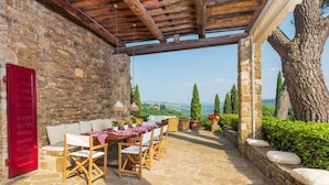 An outdoor patio with stone flooring, wooden furniture, and a view of the countryside. - Villa in Badia A Passignano with 9 bedrooms sleeps 18 (Badia A Passignano)