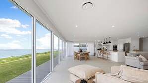 Un vaste espace de vie avec une grande fenêtre donnant sur un paysage verdoyant et la mer.