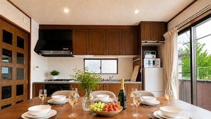 Cocina moderna con armarios de madera, una mesa de comedor preparada para seis personas y vistas al exterior.