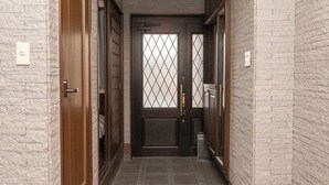 Un pasillo con puerta de madera, suelo de baldosas y pared de ladrillo.