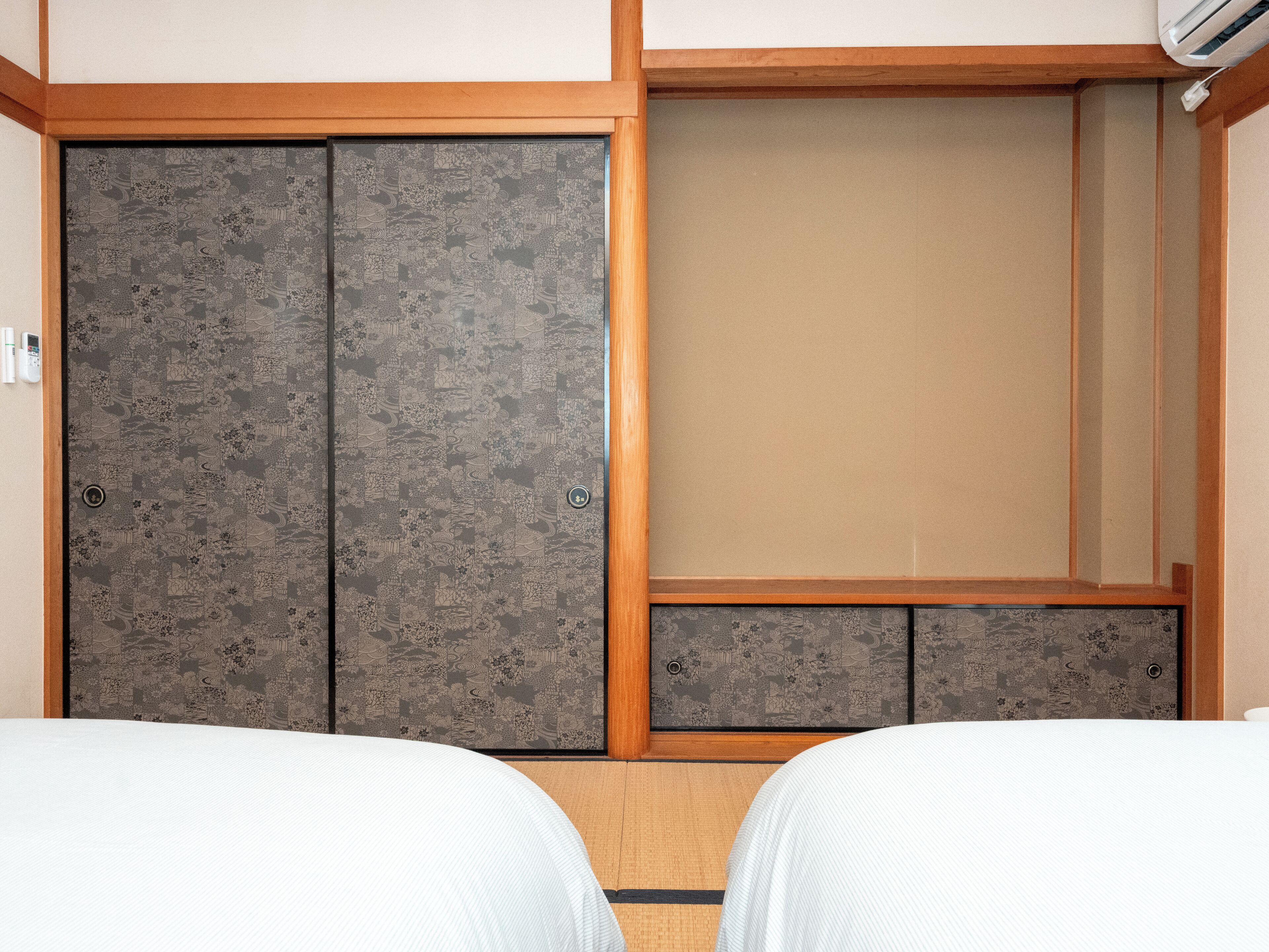 A room with two beds, a wardrobe, and a small seating area.