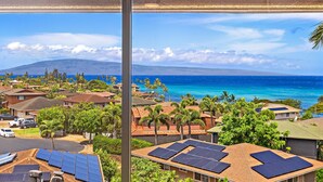 Zona residencial con casas, paneles solares y vistas al océano y a una montaña.
