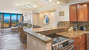 Una cocina moderna con encimeras de granito, estufa empotrada y armarios de madera.