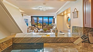 Una cocina moderna con una isla grande, un comedor con vistas y una puerta de madera.