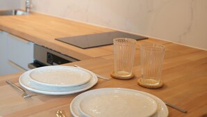 A kitchen with a wooden countertop, two white plates, two clear glasses, and a laptop.