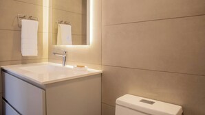 Ein modernes Badezimmer mit Waschbecken, Spiegel und Toilette in Weiß.