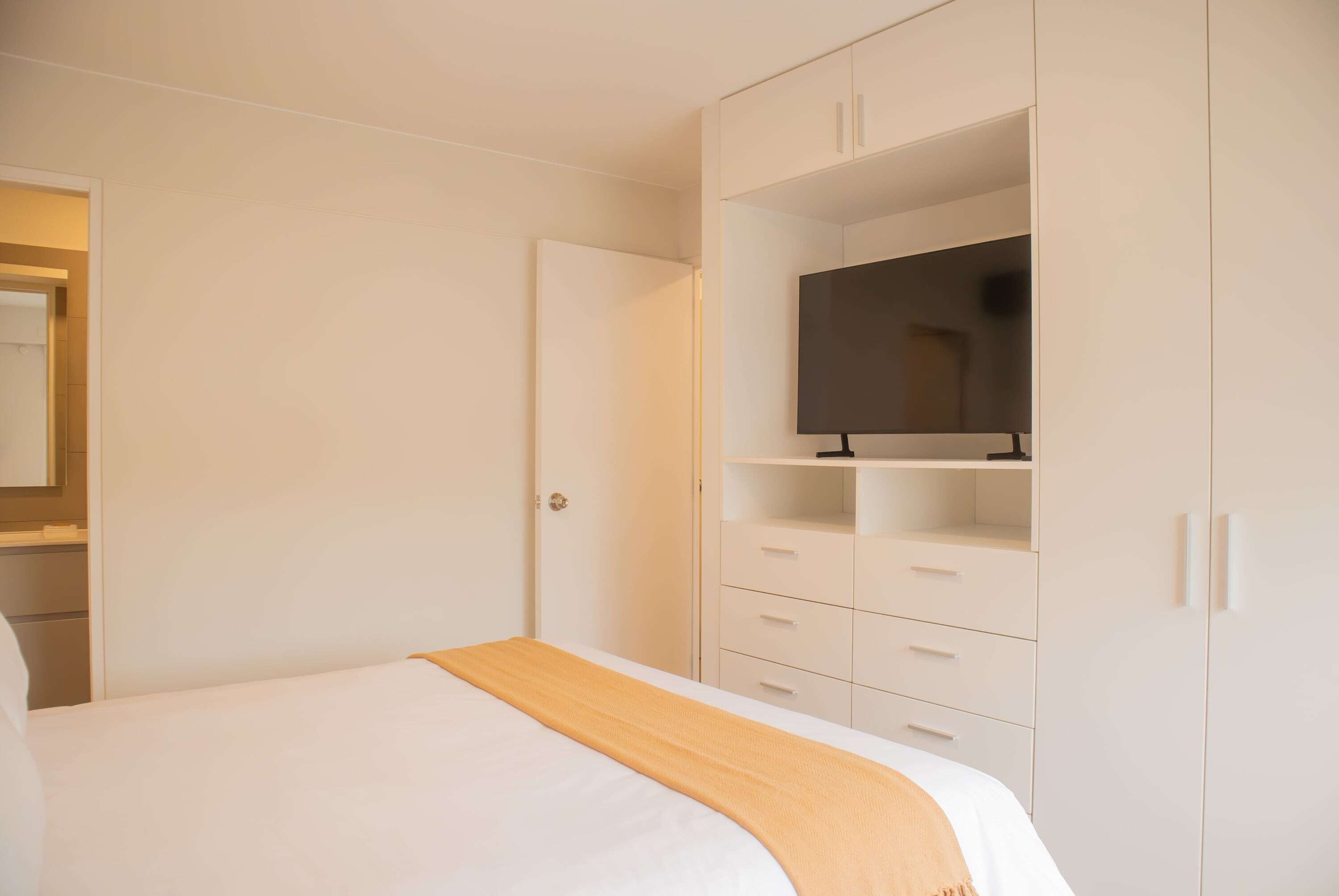 Ein Schlafzimmer mit einem Bett, einem Kleiderschrank und einem Fernseher auf einem Regal.