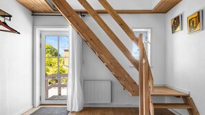 Un intérieur moderne avec un escalier en bois, des murs blancs et une vue à travers une porte vitrée.