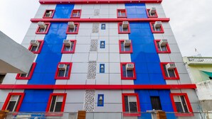 Ein mehrgeschossiges Gebäude mit modernem Design, das rote und blaue Farbtöne kombiniert, und mehrere Klimaanlagen an der Fassade sind sichtbar.