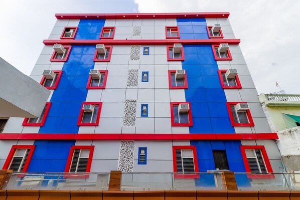 Een meerlaags gebouw met een modern ontwerp, uitgevoerd in rood en blauw, met zichtbare airconditioningsinstallaties aan de gevel.