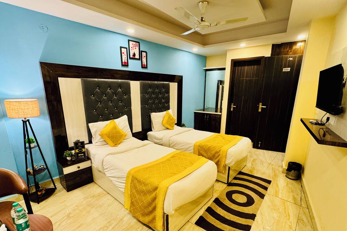 Una habitación de hotel con dos camas, televisión, escritorio y lámpara de pie.