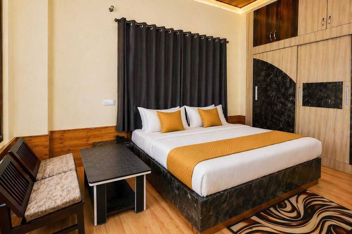 A bedroom with a bed, a small table, a bench, and a wardrobe.