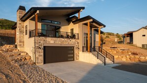 A modern two-story house with a stone facade, large windows, and a covered balcony.