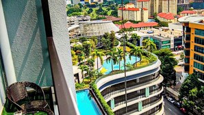 Un balcón con vista a una piscina, un edificio curvo y un paisaje urbano con un rascacielos.