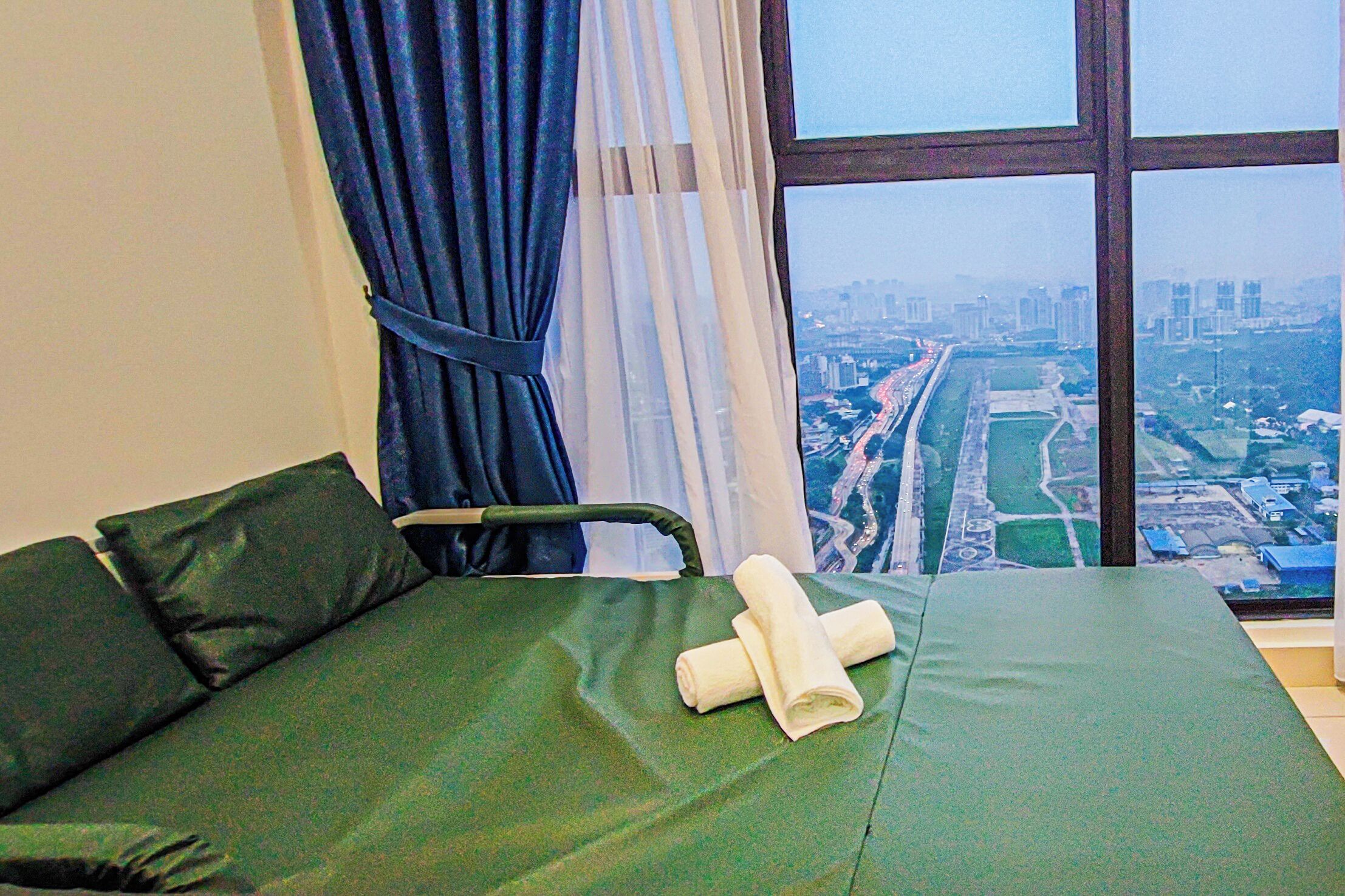 Une chambre avec un lit, une fenêtre donnant sur la ville et un rideau.