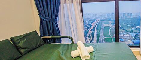 Une chambre avec un lit, une fenêtre donnant sur la ville et un rideau.