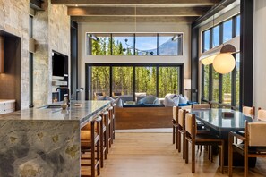 A modern kitchen with a large island, seating area with sofas, and large windows offering a view of the outdoors. - Ski-In/Ski-Out | In-Ground Hot Tub (Big Sky)
